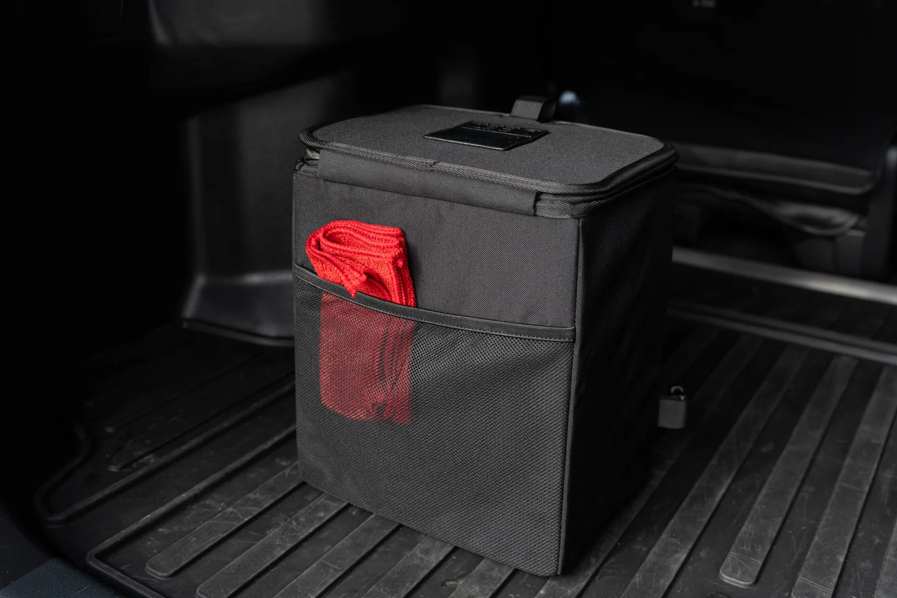 Upright Double Deez Goodz car trash can in an SUV cargo area with a red cloth in its mesh side pocket.